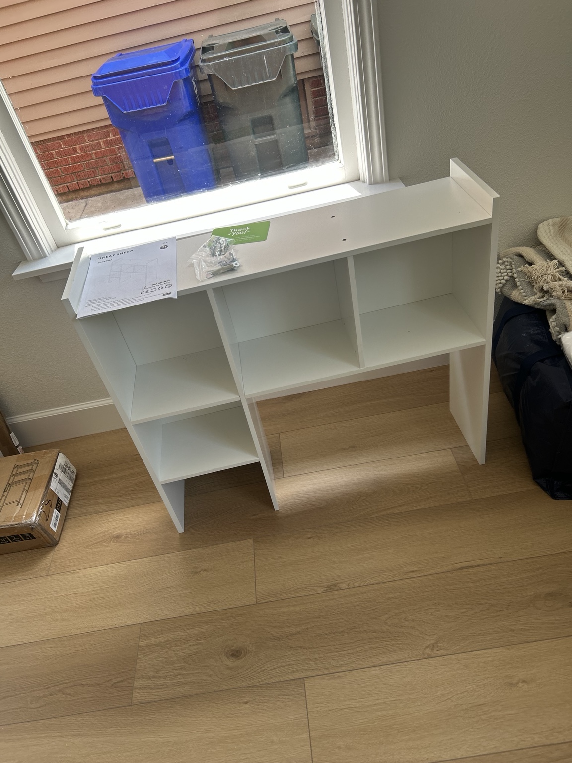 White cubby storage unit assembled beneath a window